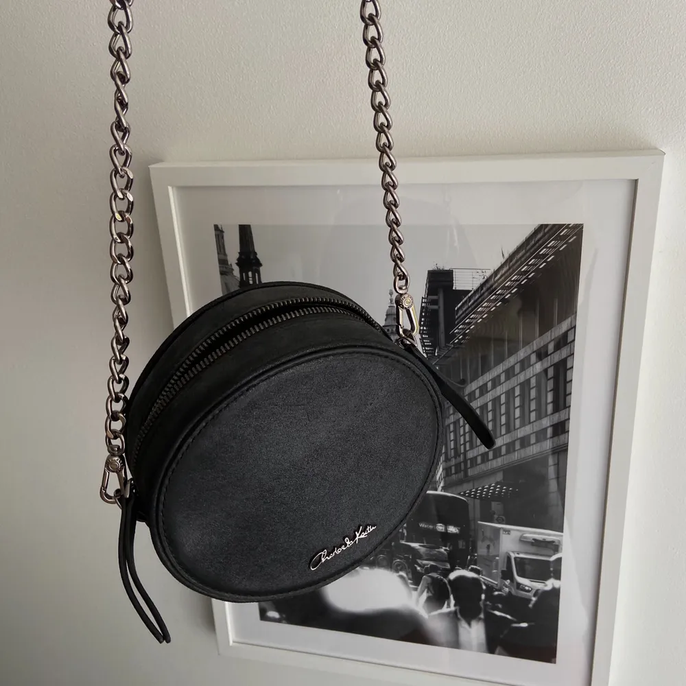 Aldrig använd i nyskick, en svart puck formad väska med svart lyster. Med ett Cross body band, Nypris 650kr . Accessoarer.