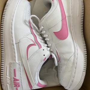 Ett par Nike air force 1 shadow i färgen white/magic flamingo storlek 40.5. Helt slutsålda överallt just nu. De är använda Max 5 gånger, det enda tecknet på användning är den lilla fläcken i den högra skon som syns på bild 2. Vid frakt tillkommer 140 kr.