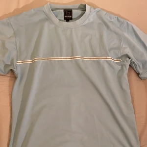 Ljusblå t-shirt - en ljusblå fin t-shirt som är gjord av mestadels polyester, med en cool reflexstripe på bröstet. frakt tillkommer!