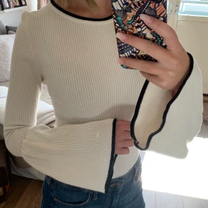 Vit topp med svarta detaljer  - Vitt topp av tjockare tyg, varm och skön till hösten. Snygga svarta detaljer. Storlek XS. 