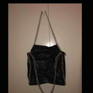  - En svart väska från tiamo med silvriga kedjor. Väskan är väldigt fint sick. Köparen står för frakten 