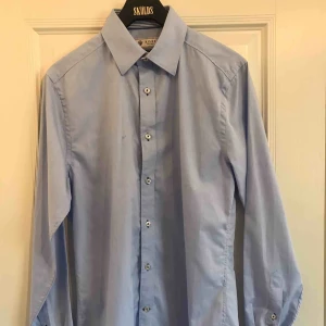  - Snygg blå slim fit skjorta från Riley. Storleken är Small. Fraktkostnad tillkommer. 