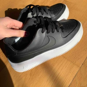 nike skor - Skor - air force 1 sage low. I svart med vit hög sula.  Säljer då de var lite trånga i tårna och går inte att lämna tillbaka, de är sjukt snygga men är använda 1 gång ute i ca 1 timme därför säljer jag skorna billigare än jag köpte dom.