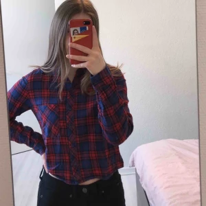  - Kort, rutig skjorta från H&M i storlek 34. Färgerna är mörkblå och röd, första bilden visar färgerna bäst. Fint skick! Fraktkostnad tillkommer