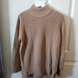 Stickad beige tröja  - Stickad beige tröja som är lite längre bak 