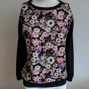 Fin svart tröja med blommor - Mönster på framsidan, svarta flätor på baksidan samt ärmar. Storlek S. 