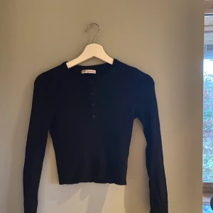 Svart croppad tröja med knappar - En svart croppad tröja med knappar från pull&bear i strl M. Frakten är inte inkluderad i priset. Det är bara att fråga om du vill ha fler bilder!