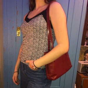 Roligt svartvitt linne - Linne/topp från H&M med svart och vitt sicksackmönster. Fint skick. Storlek S. Skönt material som sitter rätt löst på kroppen. Brottarrygg. 