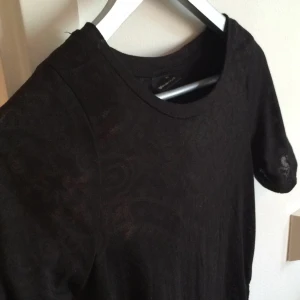  - Lite genomskinlig t-shirt som är längre baktill. Svart mönster. Står xs men passar upp till m. 