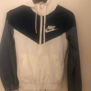 Nike vindjacka - Vindjacka från Nike. Snygg att ha till vardags men perfekt även för träning / motion. Används fåtal gånger då jag haft en liknande också. En aning smutsig men inget som inte går bort i tvättmaskinen. Sitter som en normal XS. Nypris runt 600kr. Möts upp i Solna, Stockholm eller fraktar. 