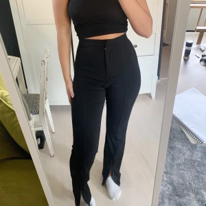 Kostymbyxor med slits från H&M - Supersnygga svarta kostymbyxor från H&M, med dragkedja vid anklarna så det går att både ha med slits och utan! Använda ett fåtal gånger så skicket är jättebra. Slutsålda i butik!!!
