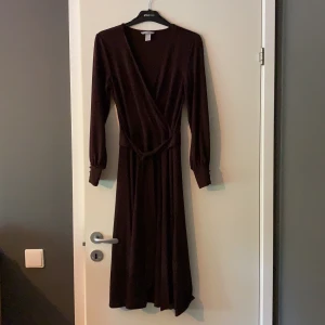 Klänning i stl S - Oanvänd mörkbrun klänning i mjukt material som gör att den faller fint då den sitter på. Denna är dock lite för liten för mig, därför säljer jag den. Den är vadlång på mig som är 165 cm lång. Nypris på HM 299:-, säljer den nu för 50:-.