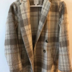 Rutig kappa - Superfin beige rutig kappa från hm. Slutar ungefär på mitten av låret.