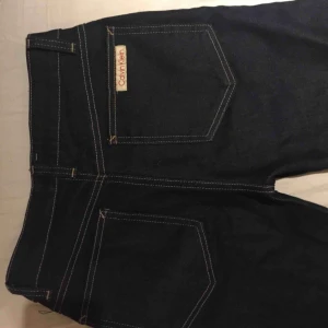  - Calvin Klein jeans i rak modell. Mörkblå, avklippta nertill. Tajta över rumpa o rak i benen, men inte för utsvängda. 