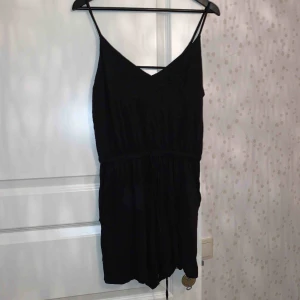  - En svart jumpsuit med strechigt material, snörning i midjan och fickor fram, V ringning både bak också fram mycket bekväm och skön!