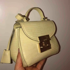  - Orm inspirerad liten rymlig väska, knappar vid sidan om, band tillkommer i samma material! 