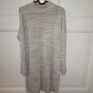  - Grå stickad klänning med hög krage och långa ärmar. Slutar en bit över knäna. Använd få gånger.  Köparen betalar frakt.