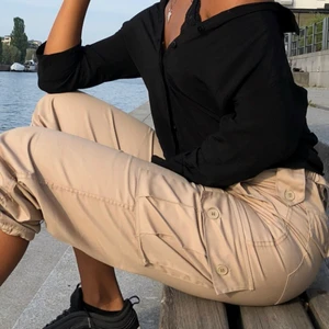 beiga cargopants  - Så snygga cargopants, NOTERA att de inte är korta som det ser ut på första bilden. De är i standard längs. Fickor bak fram och på utsidan av benen. Man kan knyta nere vid fötterna. 