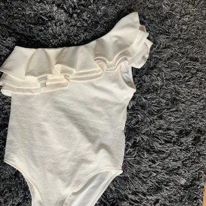 Tröja med en arm - Fin volang tröja från H&M, använd 1 gång. Body med tre fästen. Nypris 350kr, säljer för 200kr + frakt