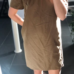 Fin off shoulder klänning från H&M beige/brun - Fin klänning stl 36. Använd med eller utan skärp. Styla som du vill offshoulder eller dra upp över axlarna. I beige/brun färg från H&M... lite khaki lik.