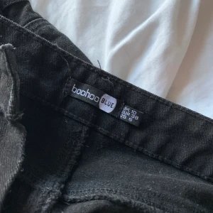 Svarta Högmidjade Utsvängda Jeans Från Boohoo! - Aldrig använda vilket är varför jag säljer de! Passar mig väldigt bra (har storlek M oftast). Frakt ingår inte i priset utan det står köparen för! Är det några funderingar så är det bara att skriva!