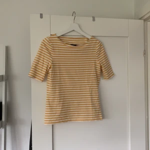 GANT t-shirt - Sommar topp med hög kvalite💗 Toppen/t-shirt har jag använt en gång och klassar den som ny💗 skulle beskriva toppen som randig med färgen vit och senapsgul/gul💗 storleken på toppen är XS
