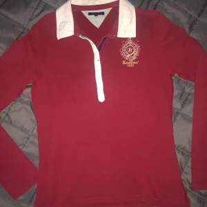 Röd pikétröja - En fin mörk/vinröd pikétröja från Tommy Hilfiger. Skönt material och fin passform. Köparen står för frakten och det angivna fraktpriset kan ändras! 