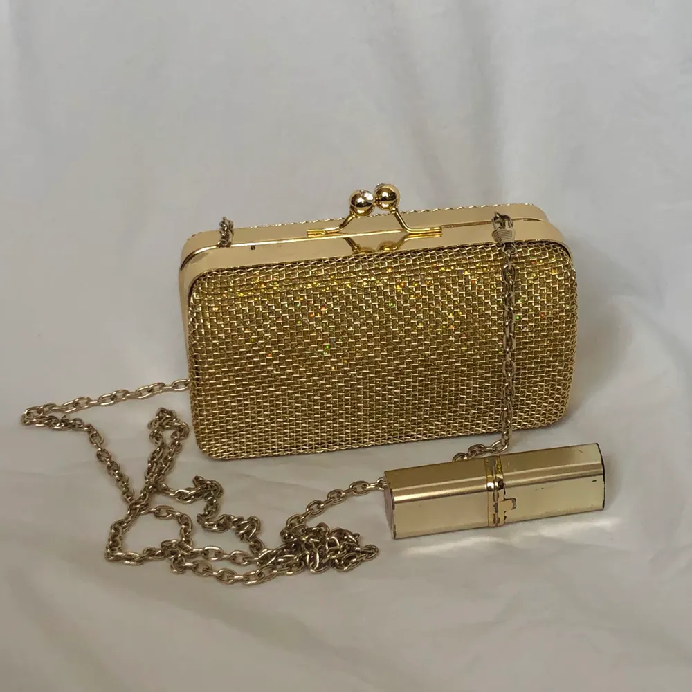 En liten söt och glimmrande guldväska med en kedja som går över axeln eller över kroppen✨ läppstiftet är med för att visa storleken✨ frakt ingår ej utan kostar 42kr✨skriv om det finns några frågor✨. Väskor.