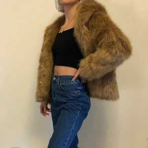Pälsjacka med hoodie - Fejkpäls köpt second hand, perfekt till vintern med stor härlig luva! Fattas en knapp längst ner sedan innan jag köpte den, men har själv inte upplevt några problem med det. Frakt tillkommer