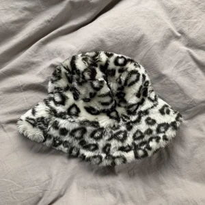 Leopard bucket hat - Fluffig bucket hat med svart vit leopard mönster. Köpt secondhand för två år sen och är i bra skick, har bara insett att jag inte använt den på sistone så väljer att sälja istället. Storlek 54 