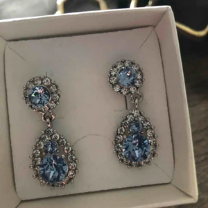  - väldigt fina Silvriga/ljusblåa örhängen från Lily and rose  Använda ca 1-3 gånger  Dom är köpta för ca 500kr  Kan mötas i nacka eller i slussen, om köparen vill ha örhängena skickade till sig står köparen för frakten:)  Betalning sker via swish