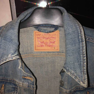  - Jeansjacka från Levi’s, nästan som ny i skick men kommer tyvärr inte till användning för mig längre. Jeansblå i färgen med silvriga knappar. Lagom passform i storlek S.