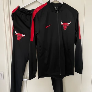 Chicago Bulls Nike Tracksuit - Chicago Bulls-tracksuit från Nike som säljes på grund av att det inte kommer till användning.  Storlek: S Skick: Väldigt bra Mått underdel: midjemått 74cm, ytterben 102cm, innerben 75cm. Överdel: plagglängd 68cm, bröstvidd 86cm, ärmlängd 54cm (armhål