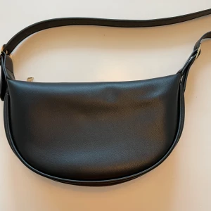 Axelremsväska  - Svart axelremsväska med guldfärgad dragkedja. Fint skick, använd 1 gång bara. 