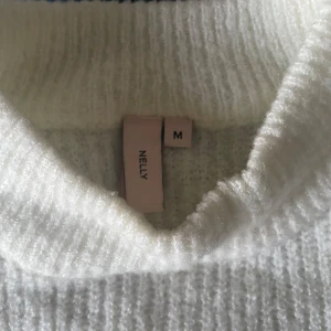 Randig stickad tröja  - En stickad tröja från Nelly som är använd ungefär 2 gånger. Storlek M och är i bra skick. Tröjan hamnar precis över midjan på mig som är 1,64.