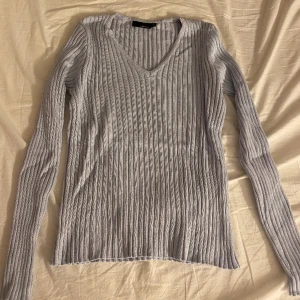 Stickad tröja  - Ljusblå kabelstickad tröja med v ringning. Använd fåtal gånger 