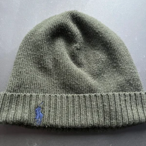 Polo Ralph Lauren mössa grön - Säljer en polo Ralph lauren mössa som är i väldigt bra skick och inte använd mycket alls. Den är i 100% merino ull och är väldigt skön att ha på sig. Skriv om ni har funderingar.