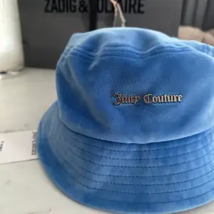 En blå bucket hat från juicy couture, passar perfekt till de mörkblå sättet🫶🏻  Helt oanvänd med prislappen kvar. Nypris: 500kr