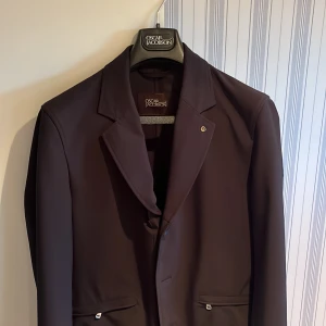 Oscar Jacobson Jacka - Tjena! Jag säljer nu min riktigt snygga hybridkavaj från Oscar Jacobson. Kavajen är gjord i windbreaker material och det finns även en spännbar luva till! Passar storlek M/L och skick 9/10. Skriv vid frågor och funderingar