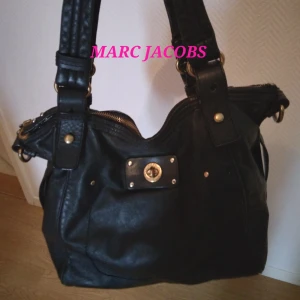 SVART ÄKTA LÄDER HANDVÄSKA, MARC JACOBS. - Svart 100% äkta Marc Jacobs handväska i läder/skinn. Fint skick dock 2 små defekter: liten detalj runt ett handtag saknas men kan ev lagas hos skräddare el skomakare + litet skrap undertill. Väskan stängs med dragkedja, har bärhandtag och axelrem.