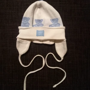 Vit vintermössa strl. 42 - En äldre vit vintermössa med nallar till bebis, ca strl 42 från Sätila kids. Ingen storlekslapp i mössan, femte bilden visar en jämförelse med en mössa i storlek 40/42 resp. 42. I fint begagnat skick. Tvättad i parfymfritt tvättmedel, ej sköljmedel