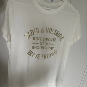 Zadig & Voltaire T-shirt ⚡️✨ - Säljer supersnygg vit t-shirt med guld tryck i strl S som tyvärr inte har kommit till användning🩷Nyskick endast använd en gång💗