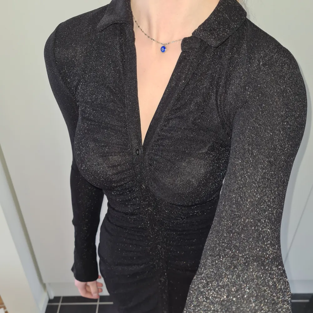 Glittrig svart klänning, långärmad med knappar. Normal i storleken, använd några få gånger. Kom med prisförslag 😊  Material: 50% Polyamid, 45% Metallfibrer, 5% Elastan. . Klänningar.