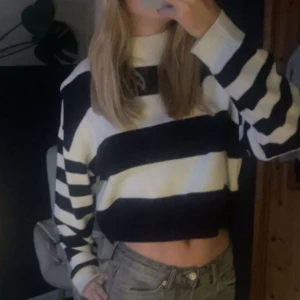 Randig stickad tröja från H&M Divided - En stickad tröja från H&M Divided med breda horisontella ränder i svart och vitt. Tröjan har långa ärmar och en rund halsringning.