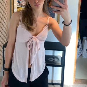 Ljusrosa linne med knytning - Säljer ett superfint ljusrosa linne med knytning framtill. Linnet har smala axelband och en lös passform som gör det perfekt för varma sommardagar. Materialet är så  mjukt och skönt. Passar både till vardags och fest!🎉