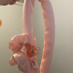 Rosa hårstylingverktyg - Säljer ett rosa hårstylingverktyg som används för att skapa lockar utan värme. Verktyget är hårt  men flexibelt, och kommer med en klämma för att hålla det på plats. Perfekt för att få fina lockar över natten eller medan du gör dig i ordning på morgonen. Instruktioner för användning medföljer. 