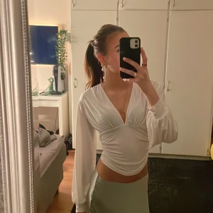 Vit omlottopp från NLY One - Säljer en superfin vit omlottopp från NLY One i storlek XS. Toppen har långa ärmar och en v-ringad design som ger en elegant look. Perfekt för fest eller en utekväll! Den är i nyskick och har en tight passform som framhäver figuren. Materialet känns mjukt och skönt mot huden.