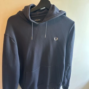 Marinblå hoodie - En marinblå Hoodie från fred perry i storlek S. Använd ett fåtal gånger.