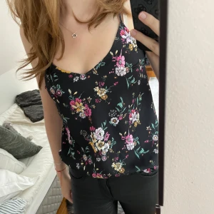Svart blommig linnetopp - Säljer detta söta svarta linnet med blommigt mönster. Toppens band går i kors på ryggen och kommer tyvärr inte till användning längre pga att den har blivit lite för liten för mig. Står ingen storlek men gissar på XS/S. Perfekt för sommaren eller fest💞