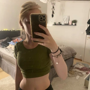 Grön croppad t-shirt - Säljer en grön croppad t-shirt. Den är tight och har korta ärmar. Perfekt för sommaren eller träning. Skicket är bra och den är väldigt bekväm att ha på sig. Passar bra till både jeans och träningskläder.